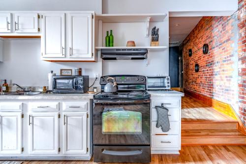 a kitchen with white cabinets and a brick wall at Jungle House Columbus Downtown Free Parking Sleeps 8 - Walk to Convention Center & Nationwide Arena - 1BR Short North Luxury Home - Over 5,800 Five Star Stays in Columbus