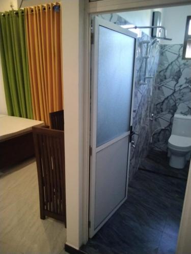 a bathroom with a door leading to a toilet at Aluthwewa Gate in Angunakolapelessa
