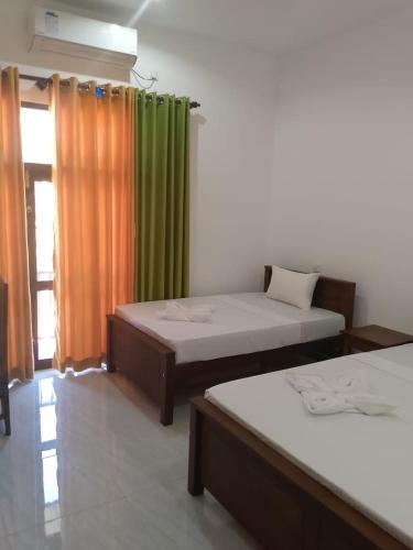 a room with two beds and a green curtain at Aluthwewa Gate in Angunakolapelessa
