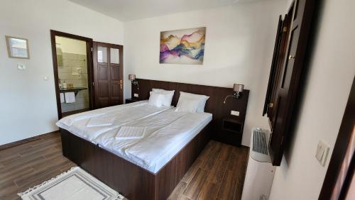 a bedroom with a large bed with white sheets at Szende Vendégház in Villány