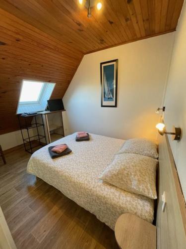 a bedroom with a bed in a room with a wooden ceiling at Le OUESSANTIN in Lampaul