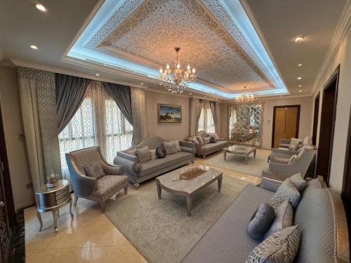 a living room with couches and a chandelier at Royal villa in Ajman