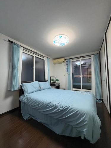 a bedroom with a bed with blue sheets and windows at sakuraの家 in Tokyo
