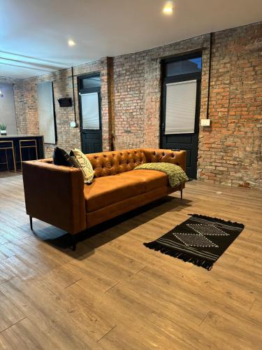 a brown couch in a room with a brick wall at Jungle House Columbus Downtown Free Parking Sleeps 8 - Steps to Convention Center & Nationwide Arena - 2BR Short North Luxury Home - Over 5,800 Five Star Stays in Columbus