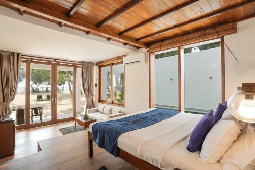 a bedroom with a large bed and large windows at Hibiscus Beach Hotel & Villas in Kalutara
