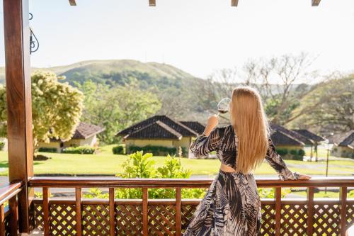 a woman standing on a balcony looking out at a house at Borinquen Thermal Resort in Liberia