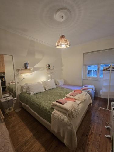 a bedroom with a bed with green sheets and a chandelier at Majesticlara Lisbon Guest House in Lisbon