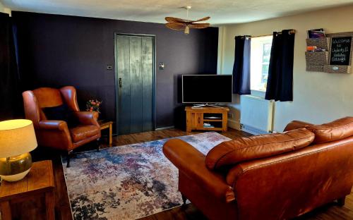 a living room with a leather couch and a television at Underhill Holiday Cottage in Whitby