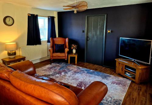 a living room with a leather couch and a television at Underhill Holiday Cottage in Whitby