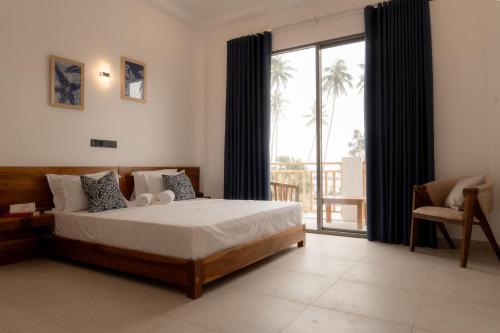 a bedroom with a bed and a balcony with palm trees at Orca Dickwella in Dickwella