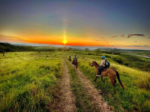 three people riding horses on a field at sunset at Borinquen Thermal Resort in Liberia