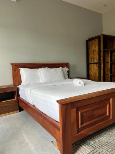 a large wooden bed with white sheets in a bedroom at Akwaaba Apartments in Chipata