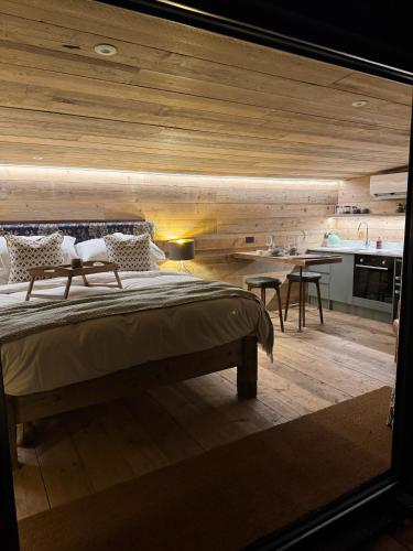 a bedroom with a large bed and a kitchen at The Goose In The Woods - With Lakeside Sauna in Wellesbourne Hastings