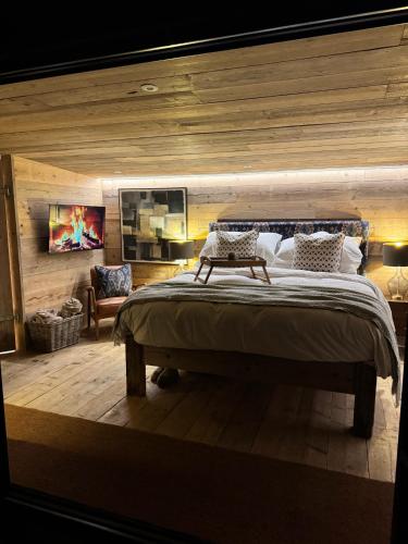 a bedroom with a large bed with a wooden wall at The Goose In The Woods - With Lakeside Sauna in Wellesbourne Hastings
