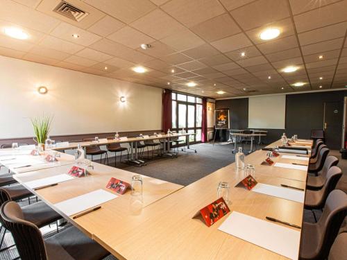 a conference room with long tables and chairs at ibis Avignon Sud in Avignon