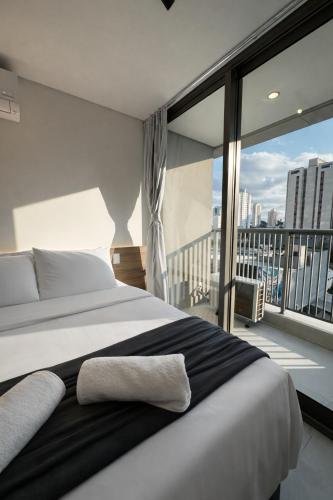 a bedroom with a large bed and a balcony at Almagah 227 - Studios de Alto Padrão no Tatuapé - SP in São Paulo
