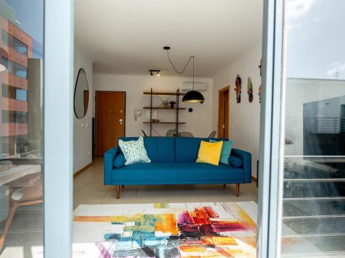 a blue couch in a living room with a window at Central Caldas w/ AC & Fast Net in Caldas da Rainha