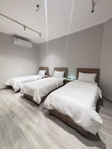 two beds in a room with white walls at شقة في دار المشاعر in Mecca