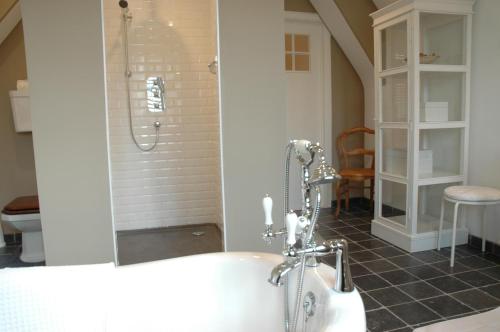 a bathroom with a tub and a shower with a sink at La Luna Guesthouse in Bruges