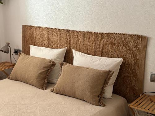a bed with four pillows and a brown headboard at Casa La Mata in La Mata