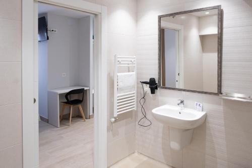a white bathroom with a sink and a mirror at Hotel La Cortijana in Logroño