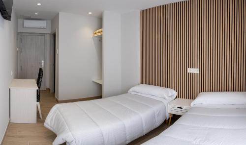 a bedroom with two beds and a wooden wall at Hotel La Cortijana in Logroño
