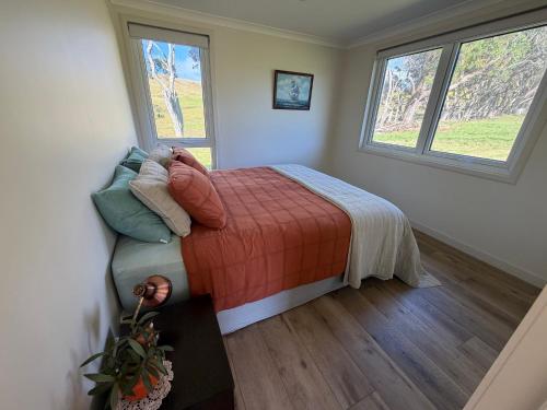 a bedroom with a bed and two windows at Pouto Farms Packhouse - Coastal Farmhouse in Pouto