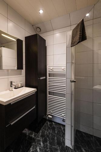 a small bathroom with a sink and a refrigerator at Zeebungalows Terschelling in Formerum