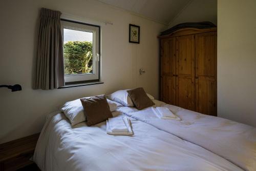 a bedroom with a white bed with two towels on it at Zeebungalows Terschelling in Formerum