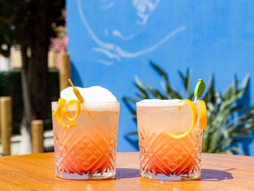 two drinks sitting on top of a wooden table at ibis Styles Perpignan Centre Gare in Perpignan