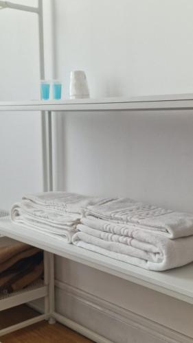 a white shelf with several white towels on it at Hospedaria 5 Bicas in Aveiro