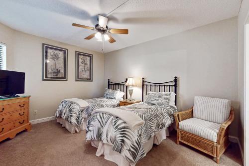 a bedroom with two beds and a ceiling fan at Oceanfront condo with panoramic views, shared pool, and private washer & dryer in Fernandina Beach
