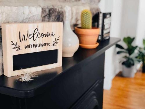 a black dresser with a welcome sign and plants on it at Jungle House Luxury Homes - Columbus Downtown Short North - Steps to Convention Center & Nationwide Arena - Sleeps up to 11 - Free Parking - Over 5,800 Five Stars in Columbus