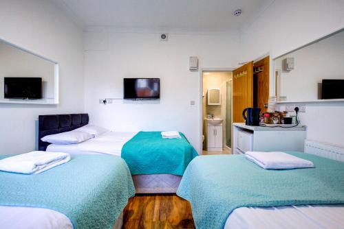 a hotel room with three beds and a television at Royal London Hotel in London