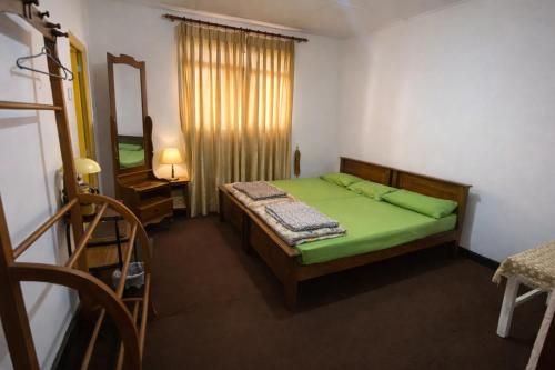 a small bedroom with a green bed and a mirror at Ora Living in Maskeliya