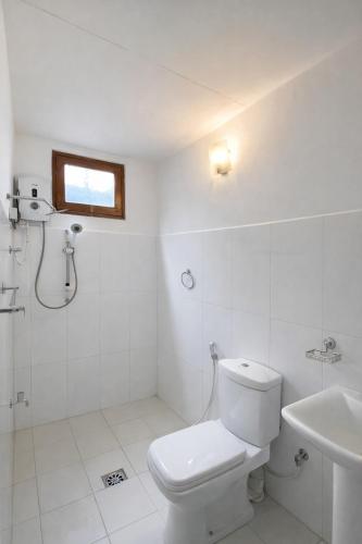 a white bathroom with a toilet and a sink at Ora Living in Maskeliya