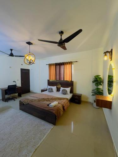a bedroom with a large bed and a ceiling fan at Rosewood Cottage in Karachi