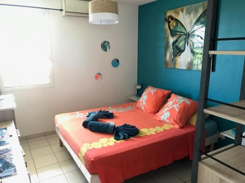 a small bedroom with a bed with a red bedspread at La bellevue in Les Trois-Îlets