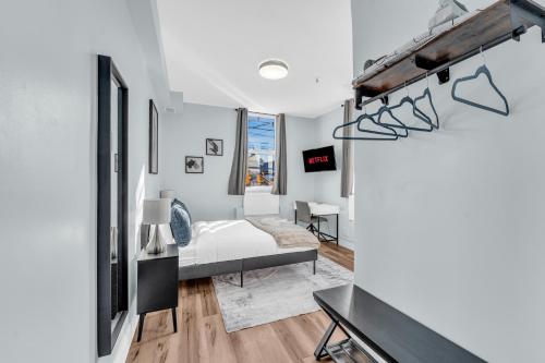a white bedroom with a bed and a desk at Guestic at Queen West in Toronto