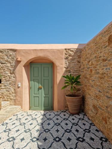 a green door with a plant next to a brick wall at Symi Village House in Symi