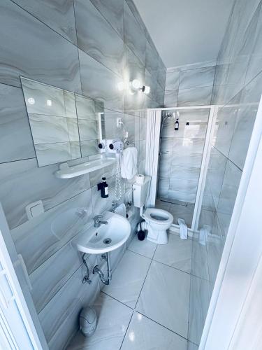 a white bathroom with a toilet and a sink at Hotel Royal in Leopoldshöhe