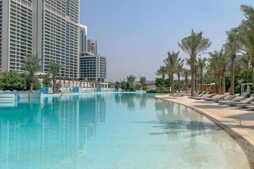 a large swimming pool with palm trees and buildings at HAVN - 2 Bedroom in Bayshore, Dubai Creek Harbour in Dubai