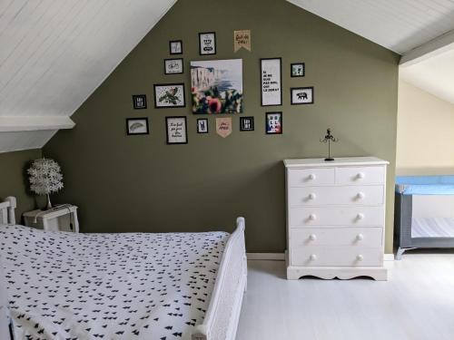 a bedroom with a white bed and a wall with pictures at Le temps des vacances in Vaudricourt