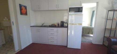 a kitchen with a refrigerator with a microwave on top at Cozy corner on Cohen in Nelson
