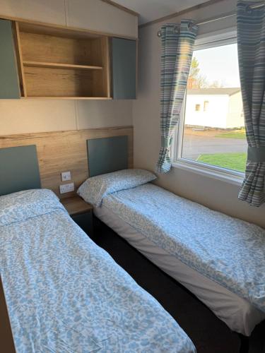 two beds in a room with a window at Coastal Caravan Seton Sands in Port Seton