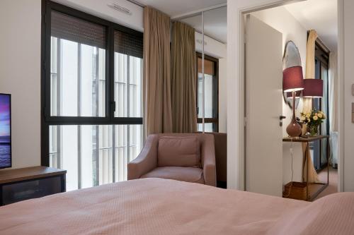 a bedroom with a bed and a chair and a window at Monaco Bliss apartments 5 min to Casino in Beausoleil