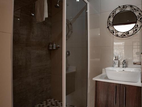 a bathroom with a sink and a shower with a mirror at The Orion Guesthouse in Middelburg