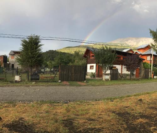a rainbow in the sky over a house at Cabaña Tío Ale MONOAMBIENTES in El Bolsón