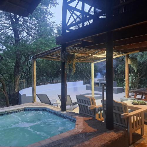 a swimming pool with chairs and a pergola at Kruger Tree Lodge in Marloth Park