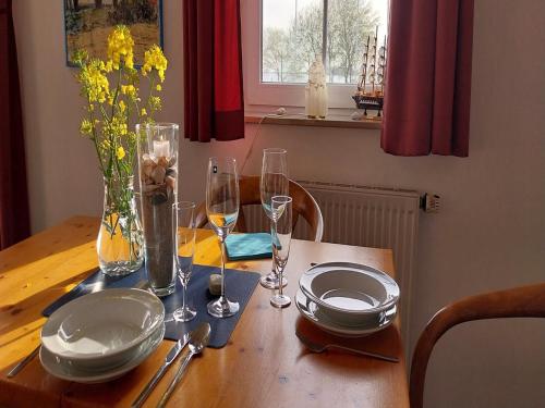 a wooden table with plates and glasses and flowers on it at Ferienanlage Orther Reede, Fehmarn-Orth in Orth